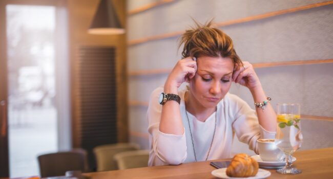 Businesswoman at coffee break having a headache She is 34 years old business woman. Stressed out from work and bad relationship. Sitting at her favorite cafe shop and trying to relax